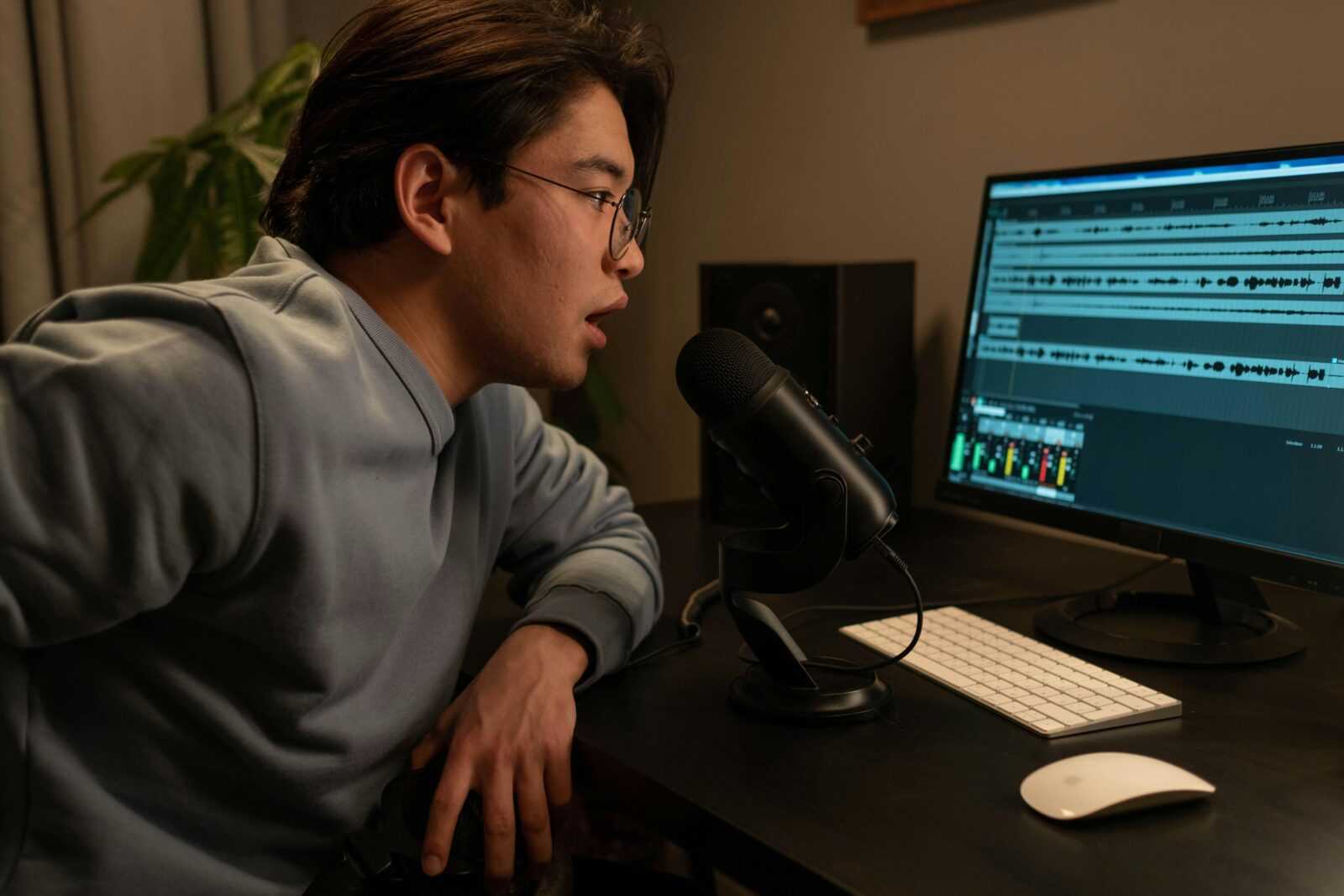Asian man using a microphone in a recording studio setting for sound engineering.